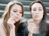 Two sad young girls smoke