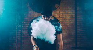 Homme soufflant un nuage de vapeur avec sa cigarette électronique