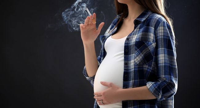 Femme enceinte en train de fumer une cigarette