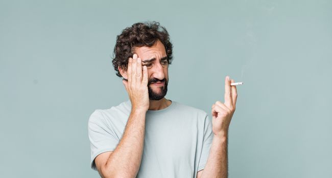 Homme faisant la grimace en fumant